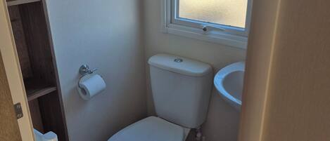 A small bathroom with a toilet, a sink, and a window.
