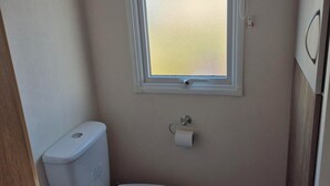 A small bathroom with a toilet, a window, and a towel rack.