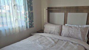 A bed with a quilted headboard and a plain wall.