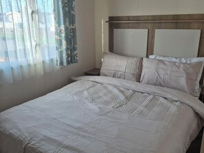 Uma cama com cabeceira acolchoada e parede lisa.