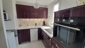 Una cocina compacta con armarios oscuros, lavavajillas, horno doble y microondas.