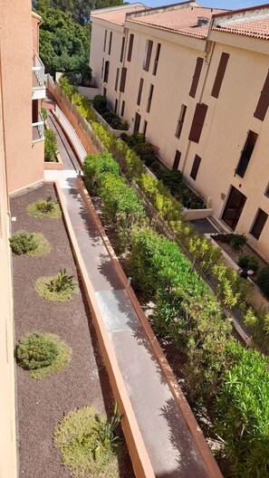 Un cortile con un vialetto, circondato da vegetazione e edifici dall'architettura uniforme.
