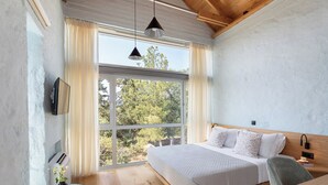A bedroom with a large bed, a wooden headboard, a bedside table, a TV, and a window with curtains. - Anassa House with Rooftop Jacuzzi (Apokoronas)