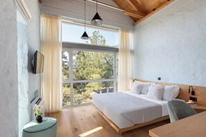 A bedroom with a large bed, a wooden headboard, a bedside table, a TV, and a window with curtains. - Anassa House with Rooftop Jacuzzi (Agios Pavlos)