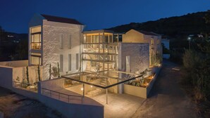 A modern multi-story house with a glass facade, outdoor seating area, and a staircase leading to the upper levels. - Anassa House with Rooftop Jacuzzi (Apokoronas)