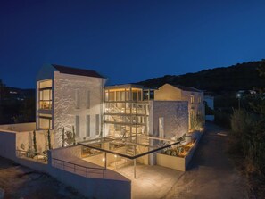 A modern multi-story house with a glass facade, outdoor seating area, and a staircase leading to the upper levels. - Anassa House with Rooftop Jacuzzi (Agios Pavlos)