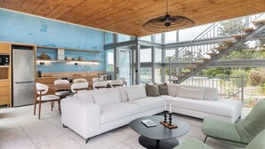 A modern interior with a wooden ceiling, a white sectional sofa, a dining area, and a staircase leading to an outdoor area. - Anassa House with Rooftop Jacuzzi (Apokoronas)