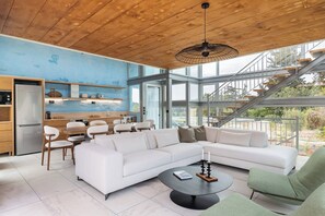 A modern interior with a wooden ceiling, a white sectional sofa, a dining area, and a staircase leading to an outdoor area. - Anassa House with Rooftop Jacuzzi (Agios Pavlos)