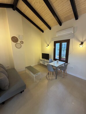 A modern living room with a sofa, a dining table with chairs, a TV, and decorative wall art. - La Corte de Isabel (Cordoba)