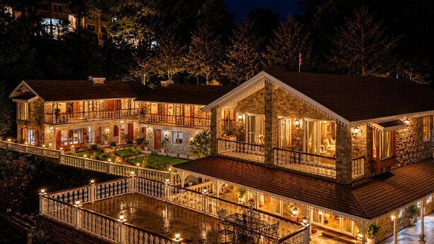 A large, multi-story stone building with balconies and a covered deck, surrounded by trees. - The Lake Heritage Naukuchiyatal (Bhimtal)