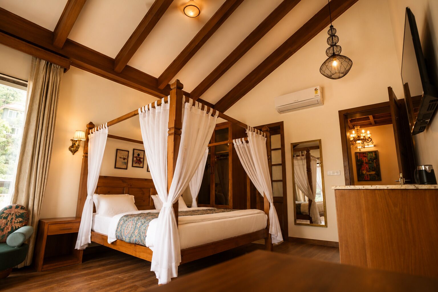 A four-poster bed with white curtains, wooden beams, a wall-mounted air conditioner, and a chandelier.