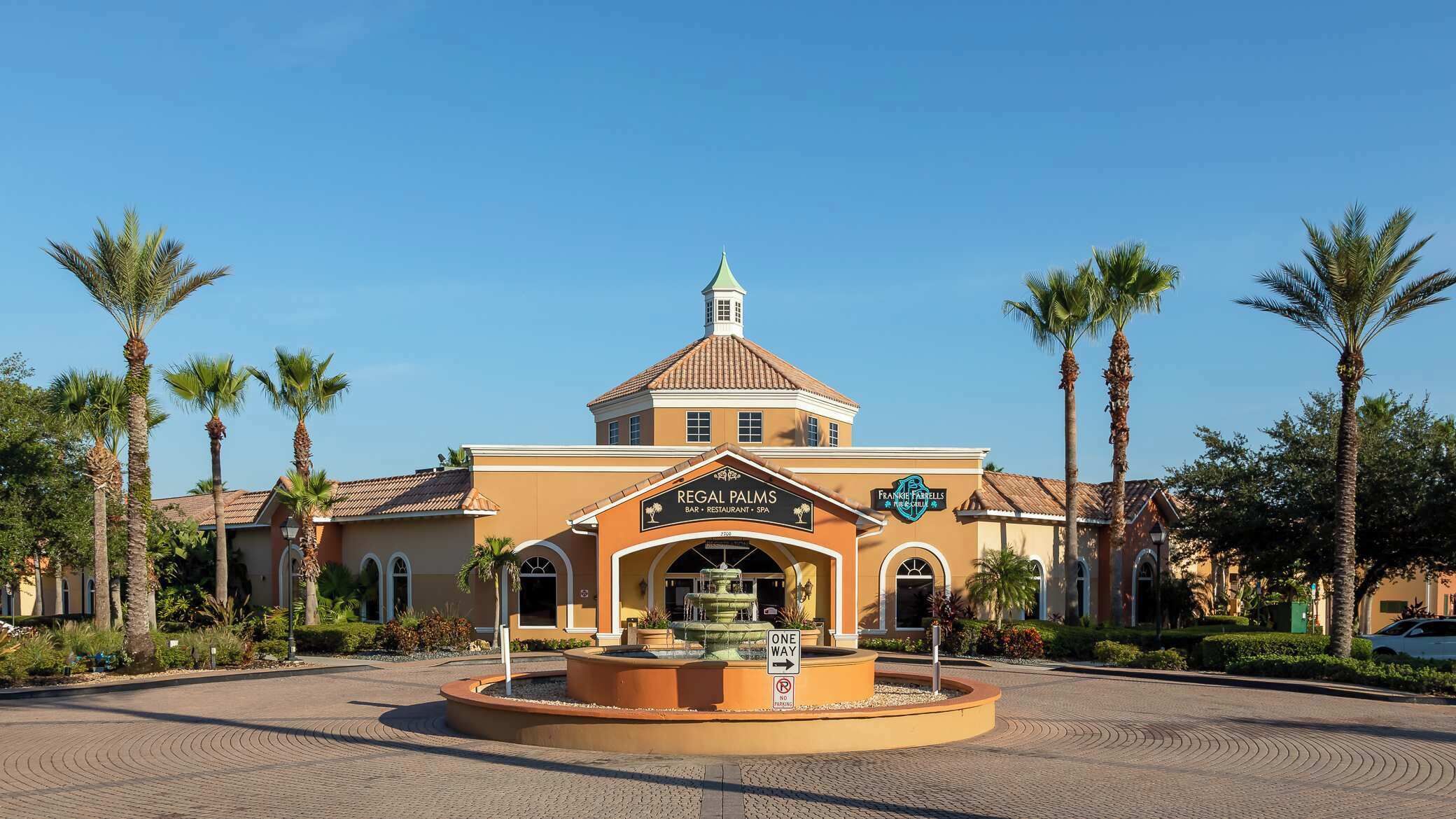 A building with a sign reading 'Regal Palms Bar, Restaurant, Spa' and 'Frankie Farrells.'