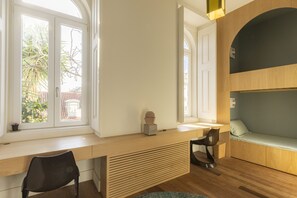 Ein Zimmer mit Schreibtisch, Stuhl, Etagenbett und Fenster mit Blick auf Bäume.