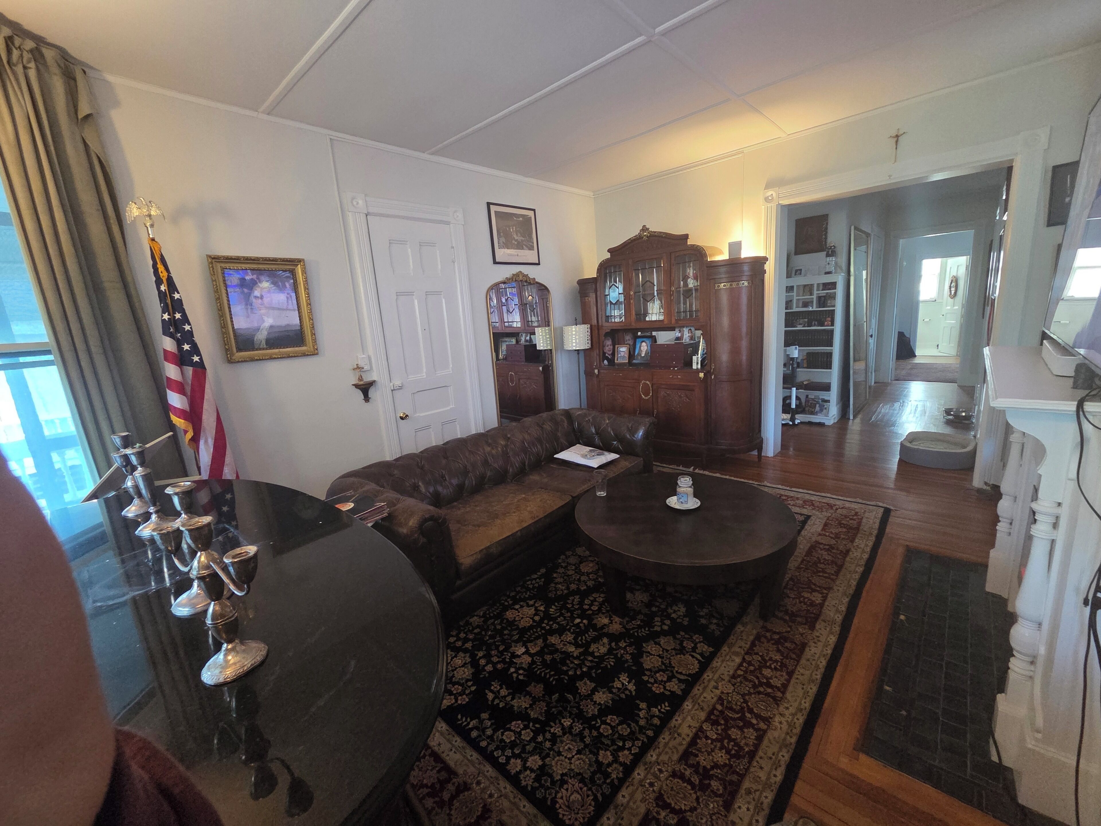 A living room with a sectional sofa, a coffee table, a cabinet, and an American flag.