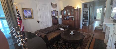 A living room with a sectional sofa, a coffee table, a cabinet, and an American flag.