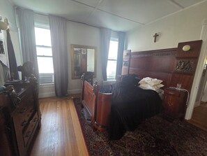 Ein Schlafzimmer mit einem hölzernen Bett, einem Schminktisch, einem Spiegel und einer Heizung.