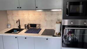 Una cocina moderna con armarios grises, un horno de acero inoxidable y un microondas.