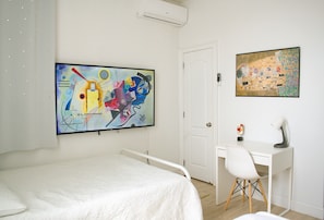 Un dormitorio con una cama, un escritorio y dos cuadros en la pared.