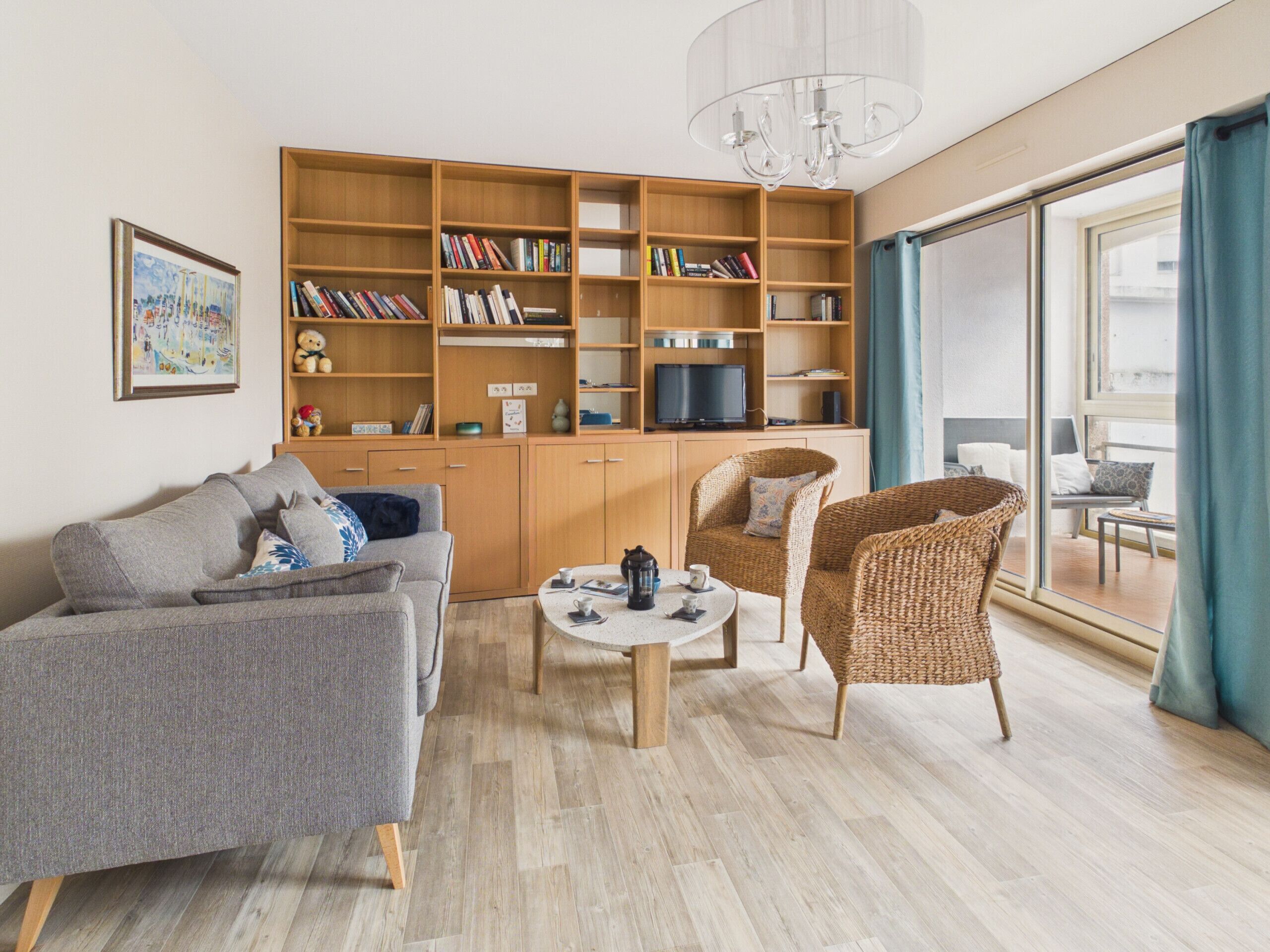 Uma sala de estar moderna com sofá, cadeiras, mesa de centro, estante e televisão.