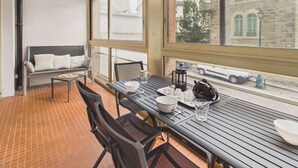 Ein Balkon mit Tisch für zwei Personen, einer Couch und Blick auf ein Steinhaus.