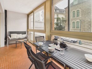 Ein Balkon mit Tisch für zwei Personen, einer Couch und Blick auf ein Steinhaus.