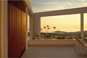 A modern balcony with a view of the sea and hills, a wooden slat wall, and a lounge chair. - Villa Five K (Primošten)