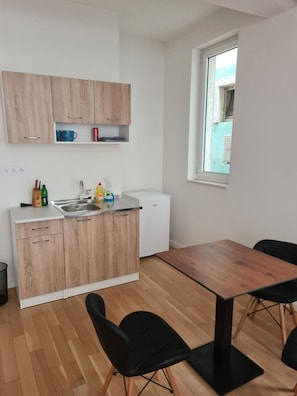 Une cuisine moderne avec des armoires en bois, un comptoir blanc et un lave-vaisselle encastrĂ©. Une fenĂȘtre offre une vue sur lâextĂ©rieur.