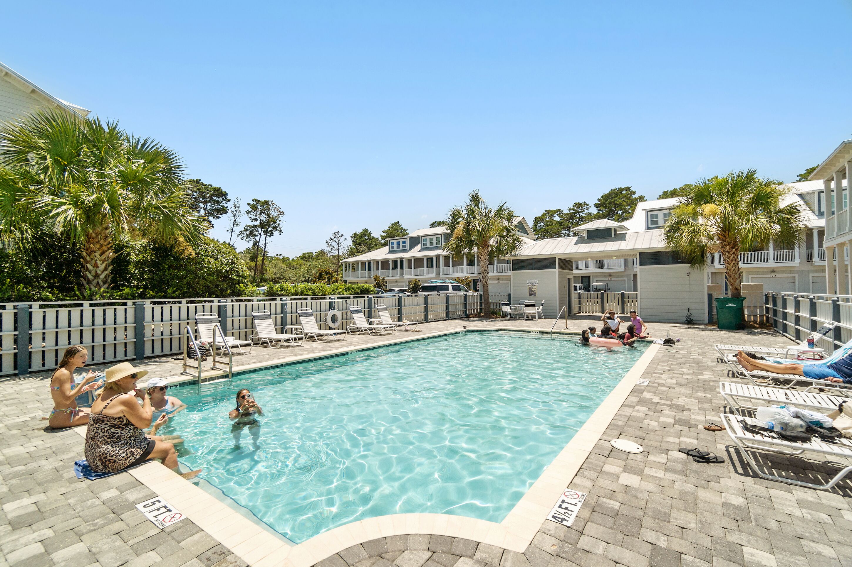 A swimming pool with lounge chairs and palm trees.