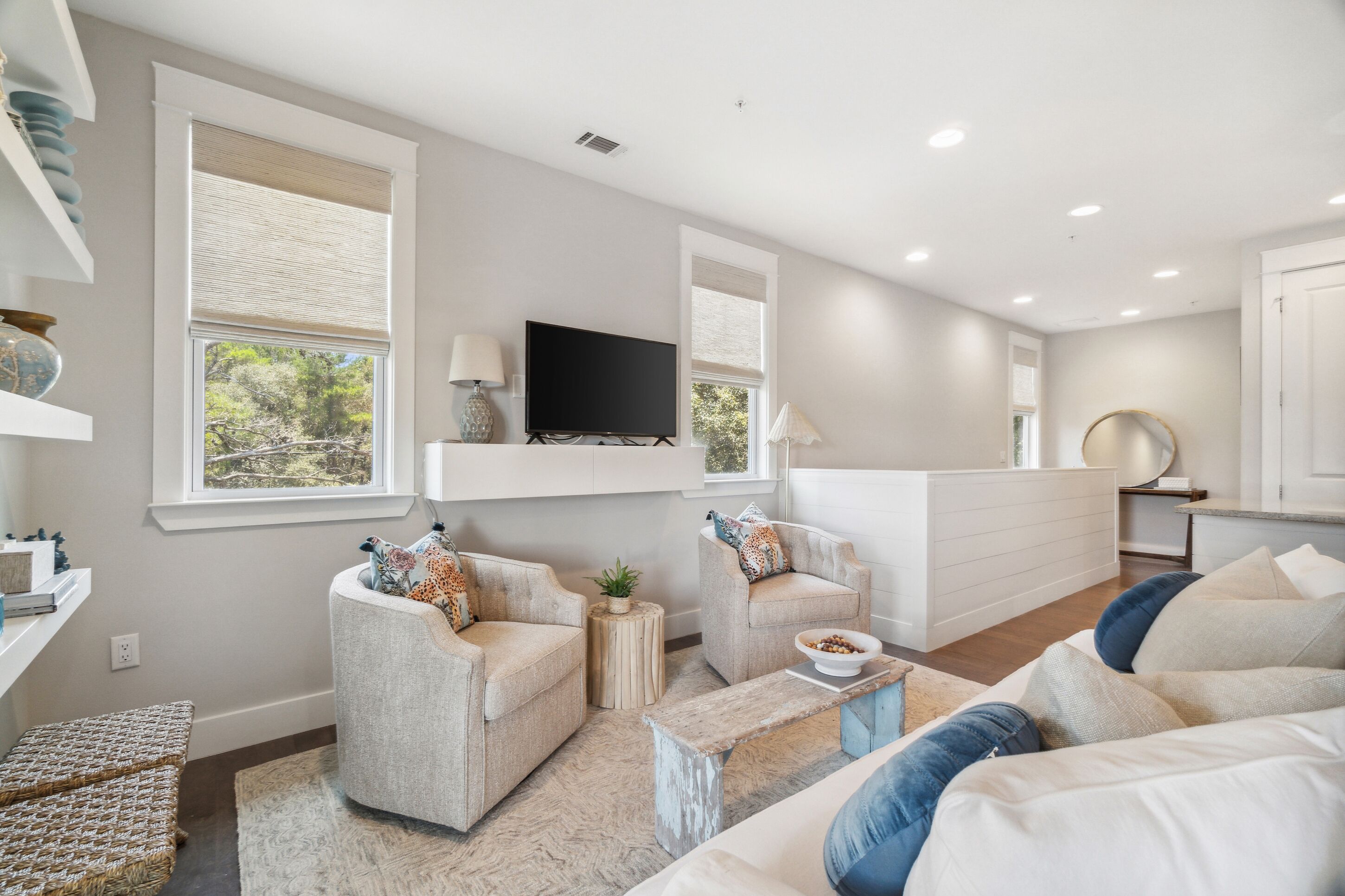 A modern living room with two armchairs, a sofa, a coffee table, and a flat-screen TV mounted on the wall.