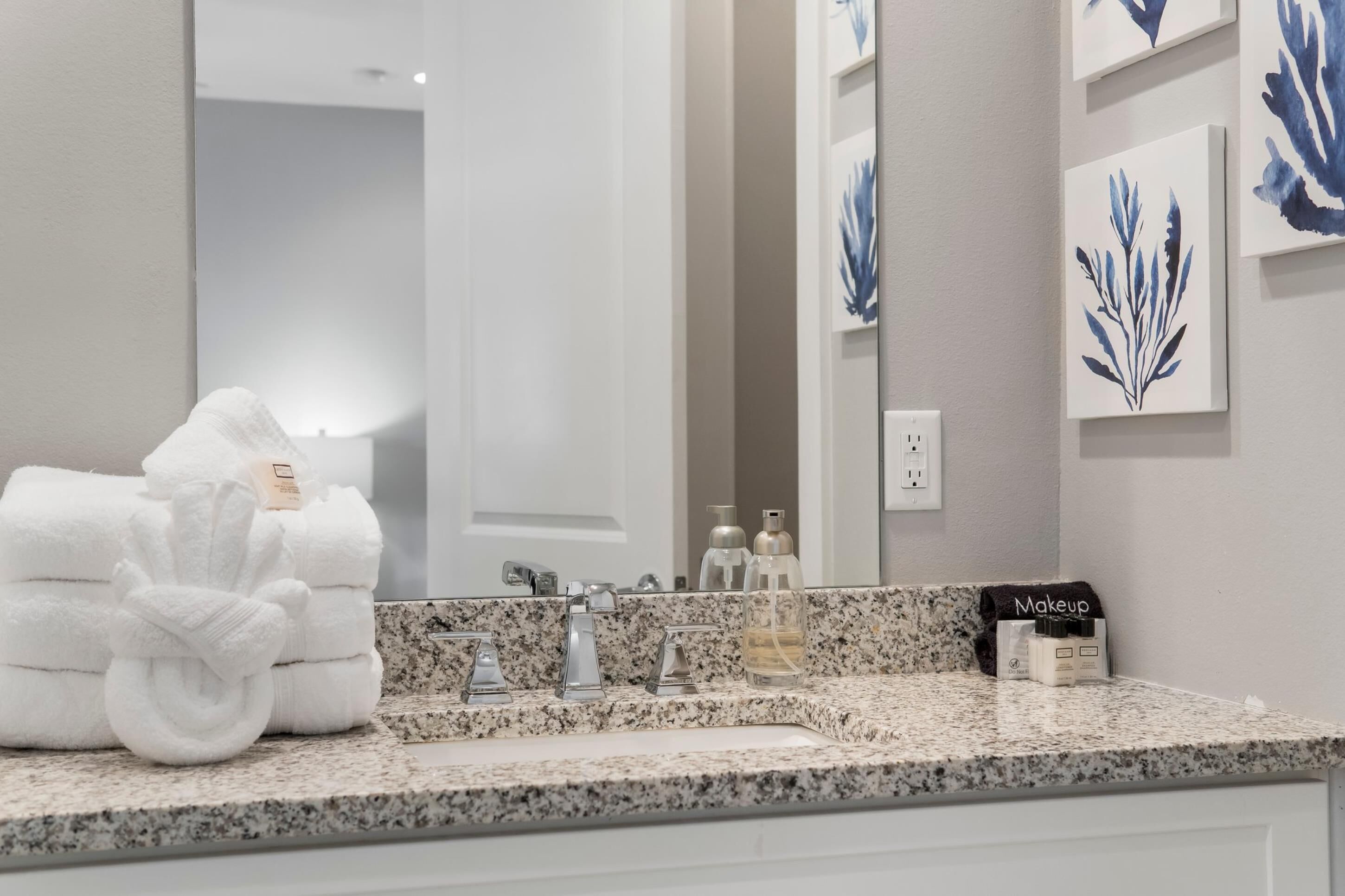 A bathroom with a granite countertop, a sink, a mirror, and towels.