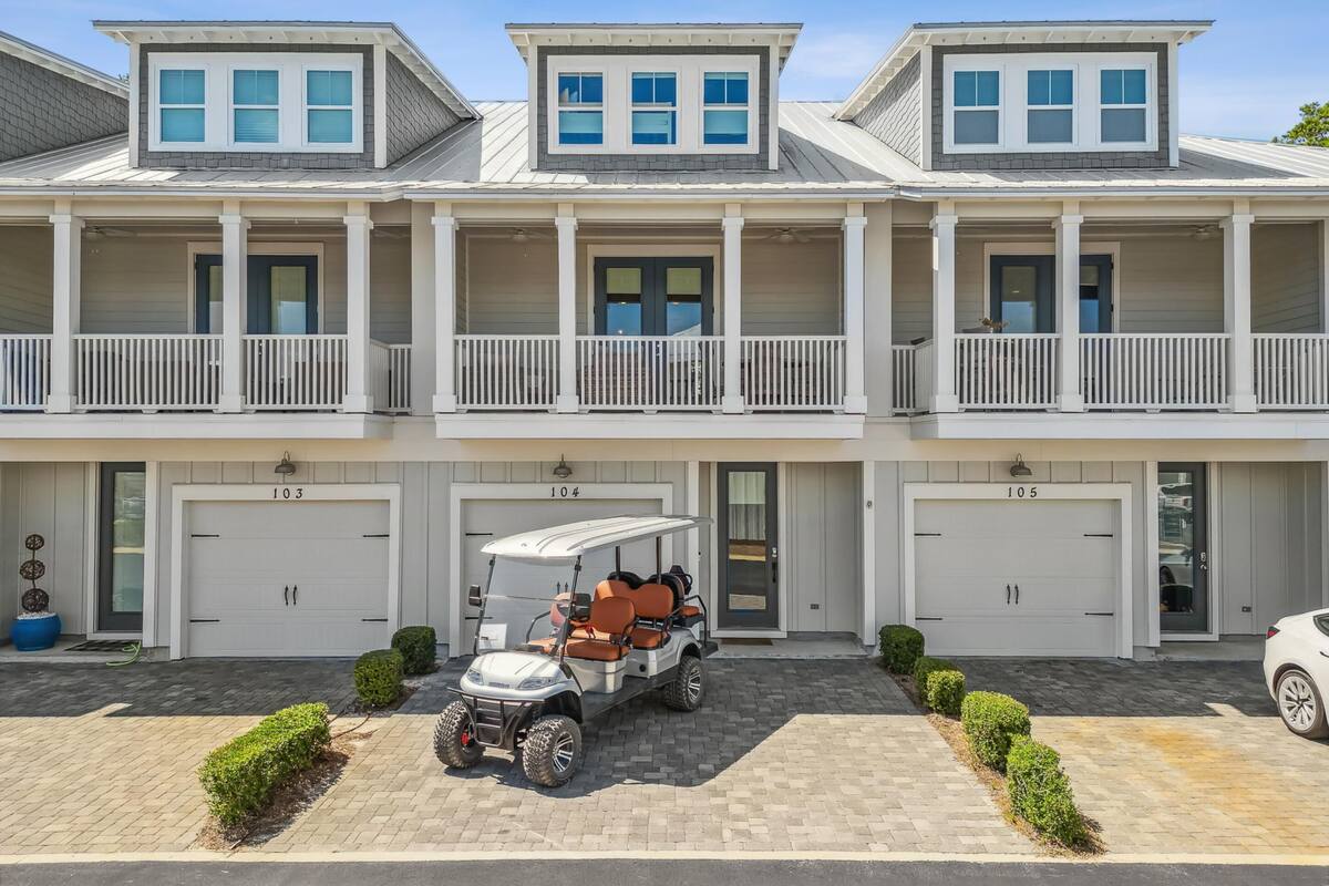 A multi-story residential building with a central entrance, two garages, and a covered parking area.