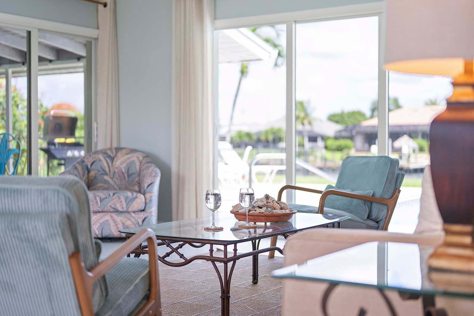 A sunlit room with a glass table, two chairs, and a view of the outdoors.