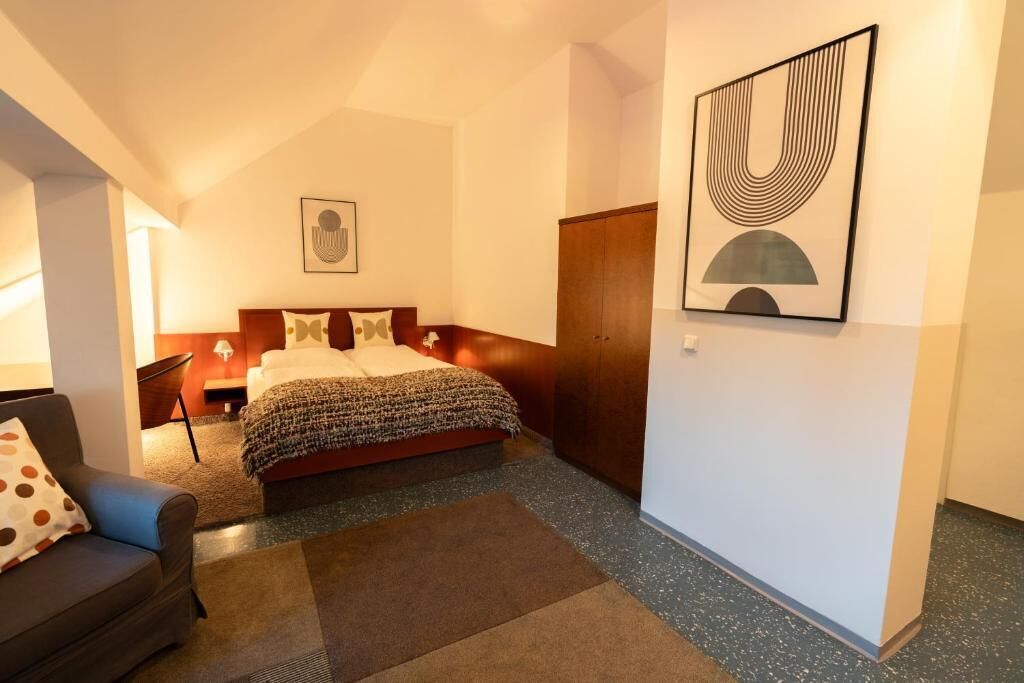 Un dormitorio con cama, sofá, armario y un cuadro en la pared.