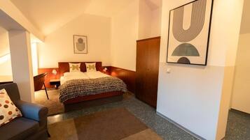 Un dormitorio con cama, sofá, armario y un cuadro en la pared.