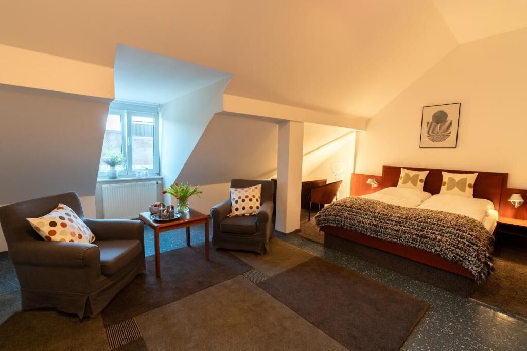 Una moderna camera d'albergo con un letto, due poltrone, un tavolino e una finestra.