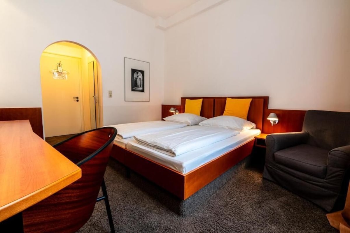 Una habitación de hotel con cama, escritorio, silla y puerta.