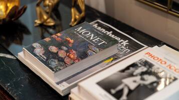 Una revista anomenada 'Handwerk' sobre una superfície de marbre amb figures daurades decoratives i una fotografia emmarcada al fons.