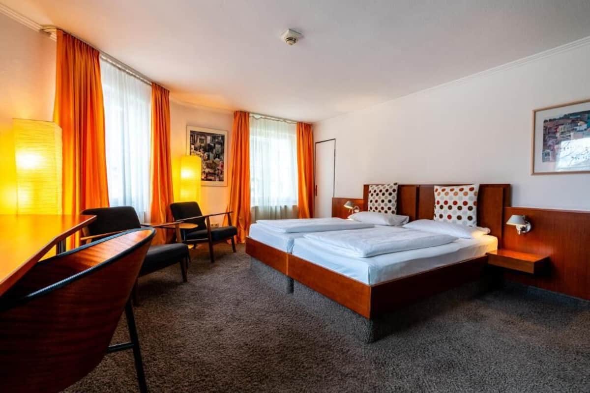 Una camera d'albergo con un letto matrimoniale, una scrivania con sedia e un tavolino.