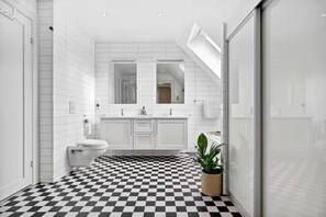 A modern bathroom with a checkered floor, white tiles, a large mirror, and a potted plant. - 3-bedroom apartment in Stavanger city center (Rogaland)