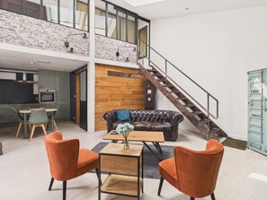 Ein Loft-Wohnbereich mit Treppe, einem Esstisch und einem Ledersofa.