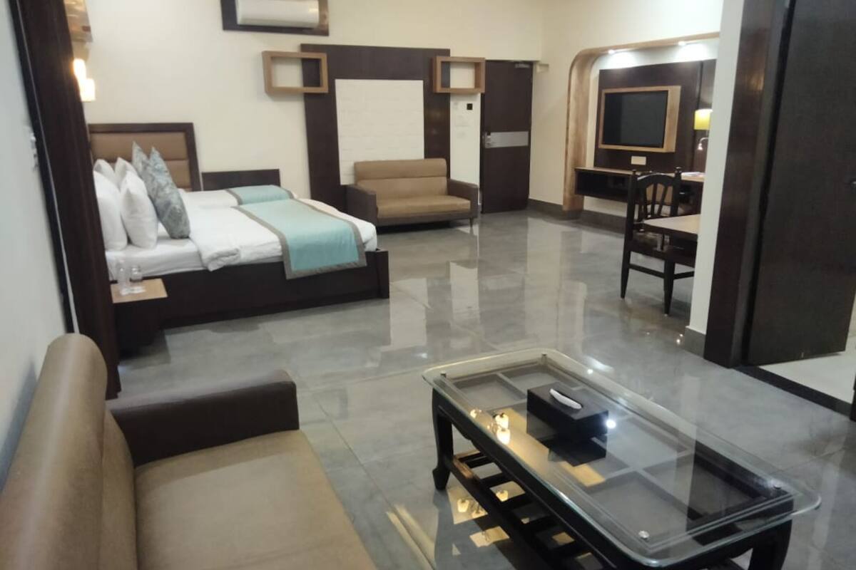 Una habitación de hotel moderna con una cama, un sofá, una mesa de centro de vidrio, un televisor y un escritorio.