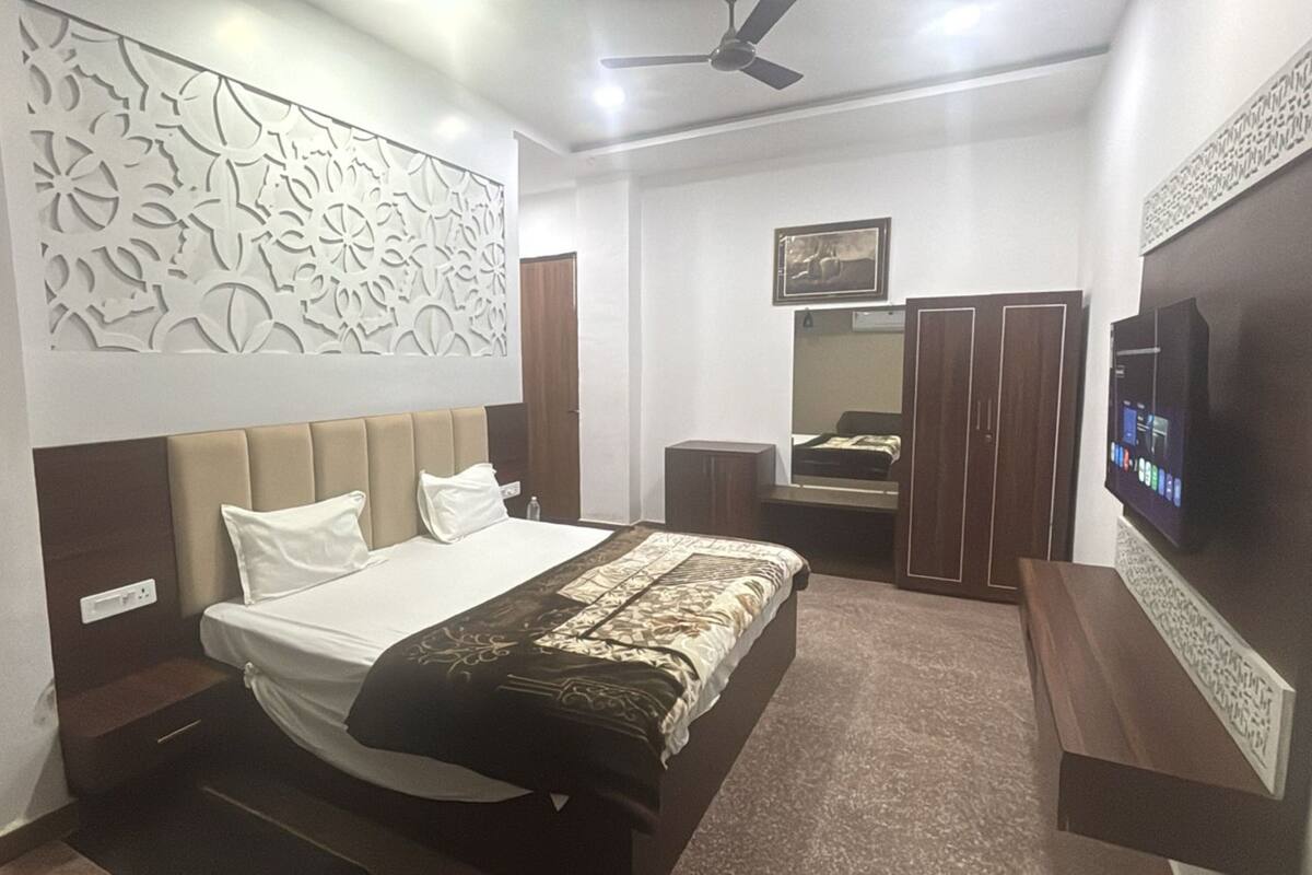 Un dormitorio con cama, armario, espejo y televisión.