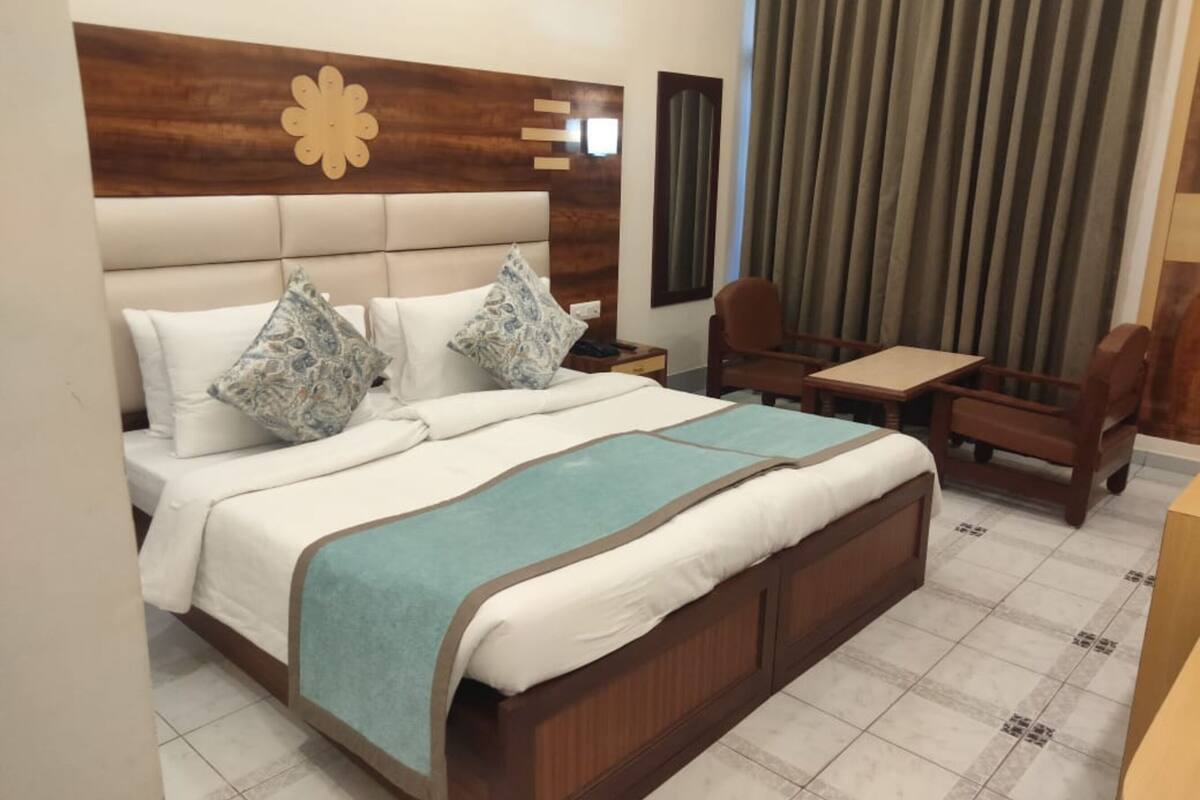 Una habitación de hotel con una cama grande, cabecera de madera, un escritorio y una silla.