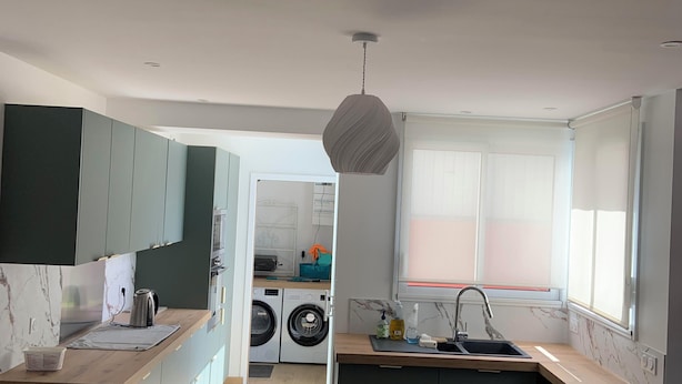 A modern kitchen with a central island, built-in appliances, and a view into the laundry area.