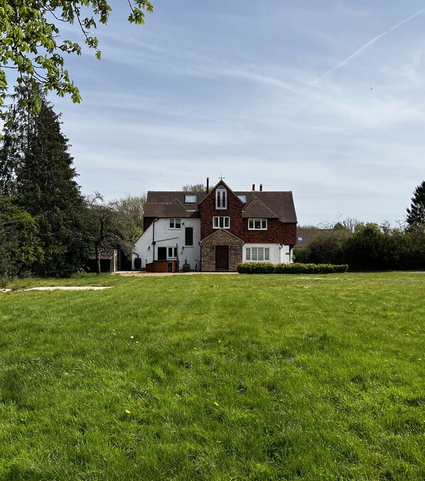 A two-story house with a large front lawn, a chimney, and a satellite dish.