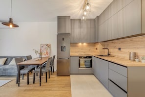 Eine moderne Küche mit Einbauofen, Kühlschrank und Essbereich inklusive Tisch und Stühlen.