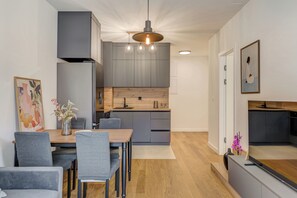 A modern kitchen with grey cabinets, a wooden countertop, and a hanging light fixture. - The Oak Haven (Split)