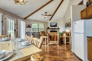 A dining area with a wooden table, chairs, and a fireplace. - Octagon Chalet: Hot Tub, Pool Table & Stunning Mountain Views - Sleeps 6 (Gatlinburg)