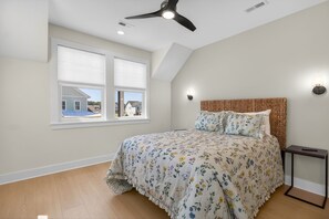 Ein Schlafzimmer mit Bett, Deckenventilator, Fenster und Nachttisch.