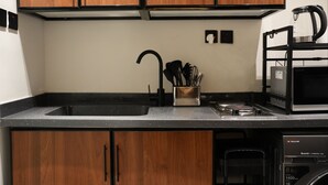 Ett kök med träskåp, en svart bänkskiva, en diskho, en kaffebryggare och en diskmaskin.